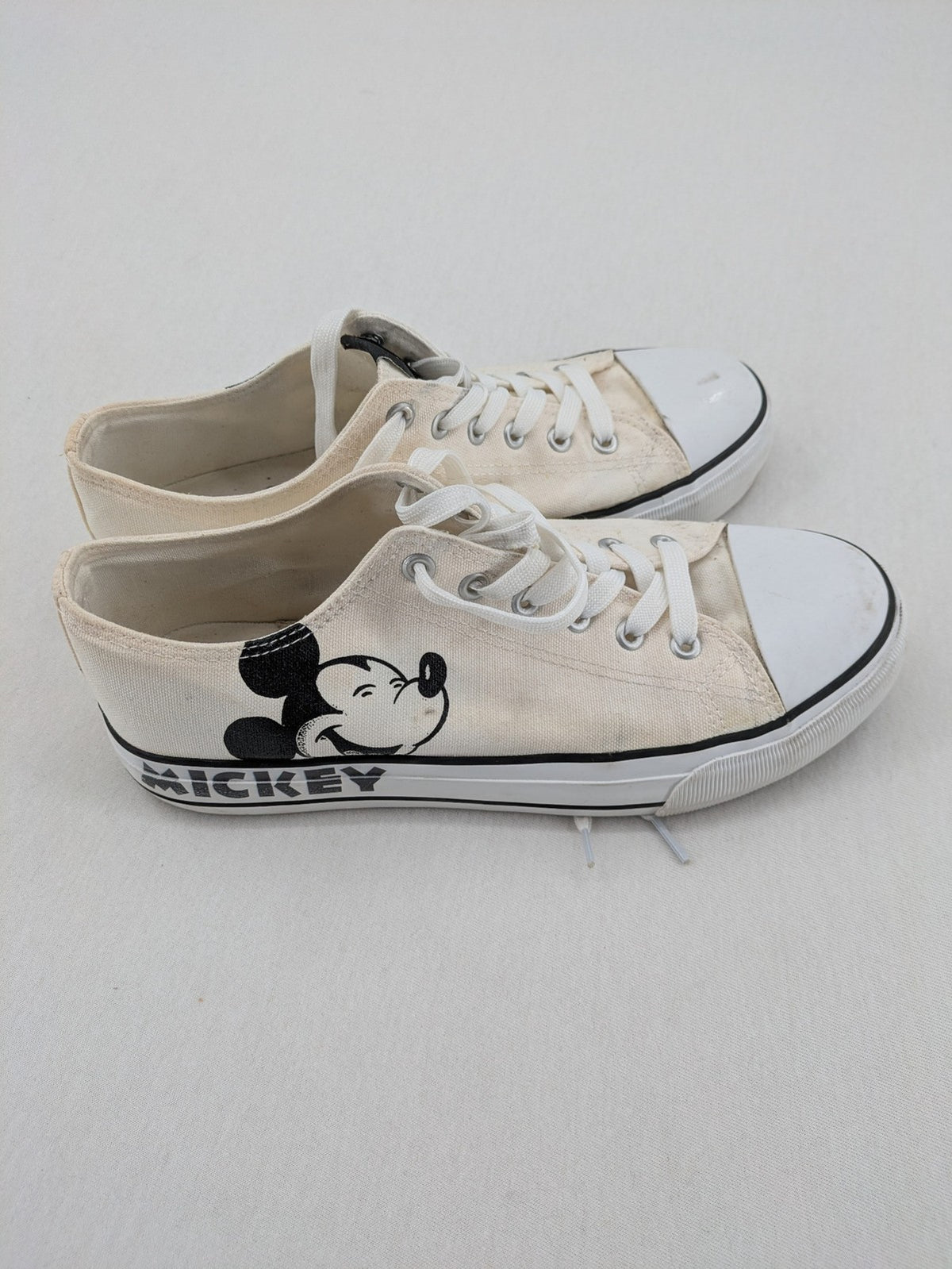 Disney Mickey Mouse white canvas low top sneakers with iconic Mickey Mouse graphic.
