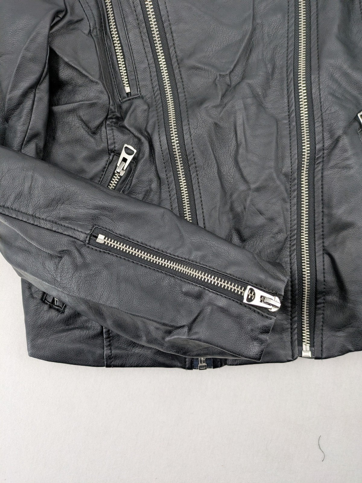 H&M black biker jacket with silver zippers, shoulder flaps, and snap-button details.