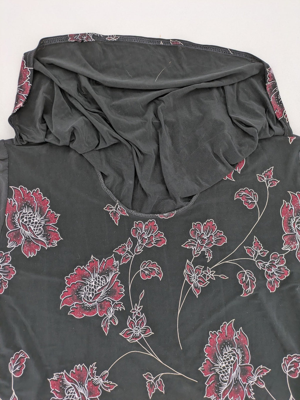 Damen black top with burgundy and white floral print, waterfall collar, and ruffled sleeves.