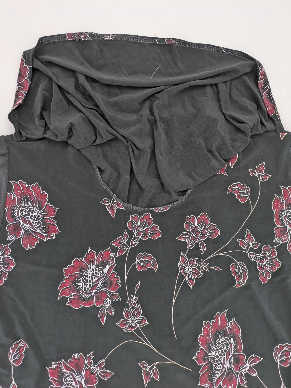 Damen black top with burgundy and white floral print, waterfall collar, and ruffled sleeves.