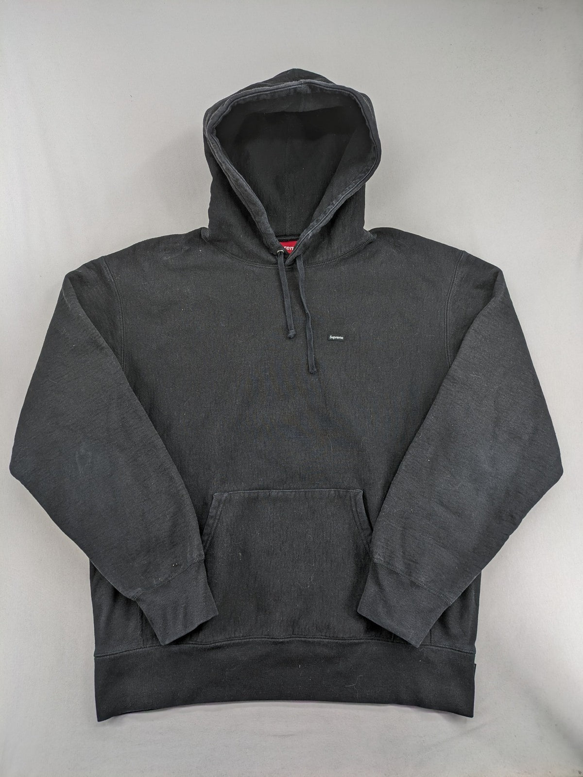 Supreme grey hoodie with embroidered small box logo, kangaroo pocket, and ribbed cuffs.