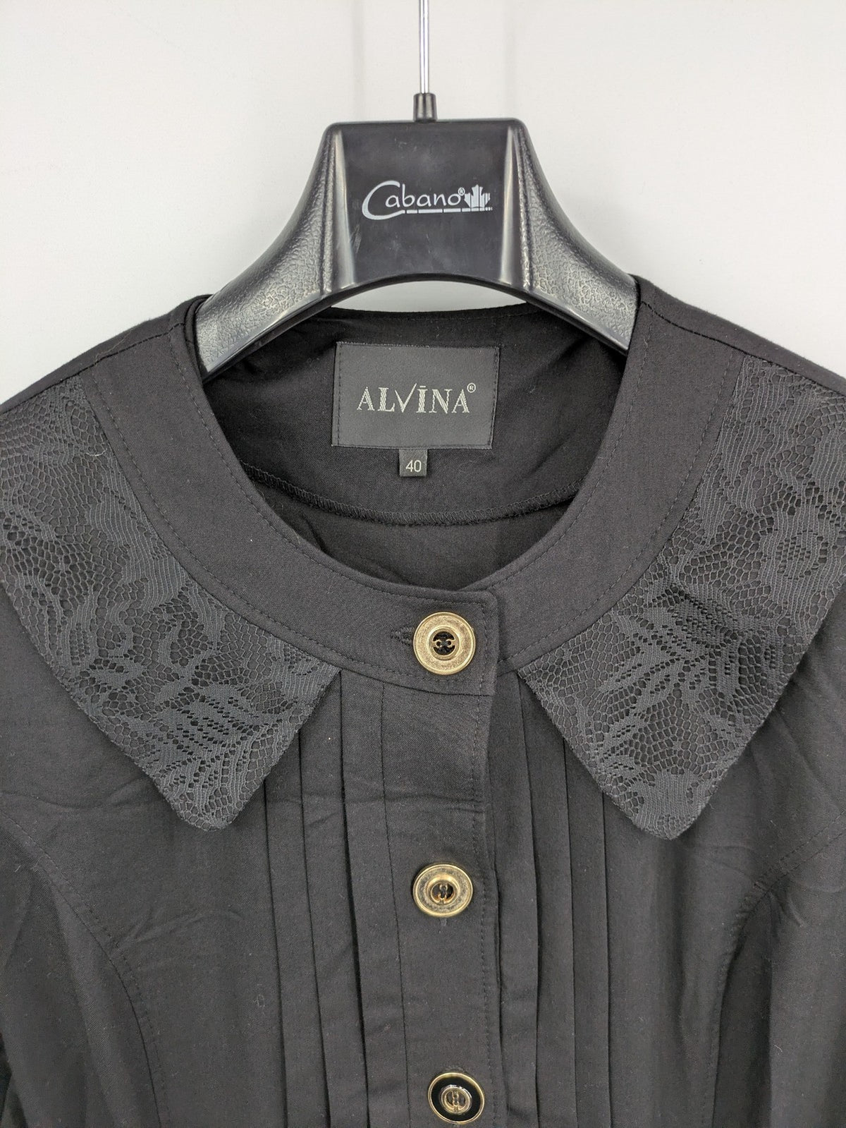 Alvina black trench coat with lace collar and gold buttons, belted waist design.