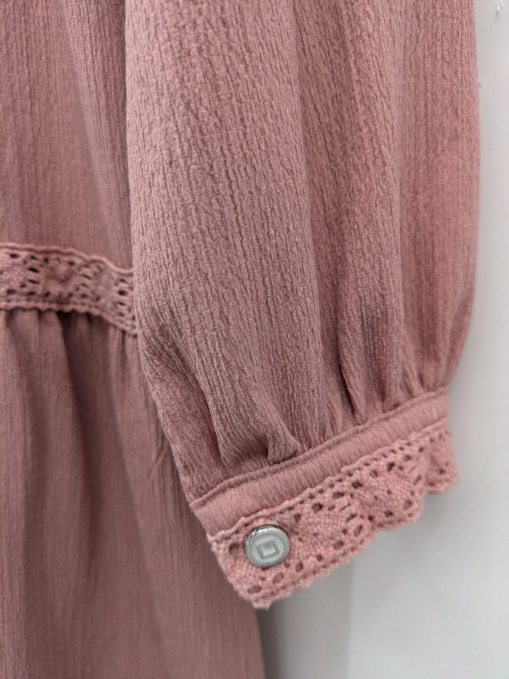 Moda pink bridal party dress with lace inserts, long sleeves, and tiered design.