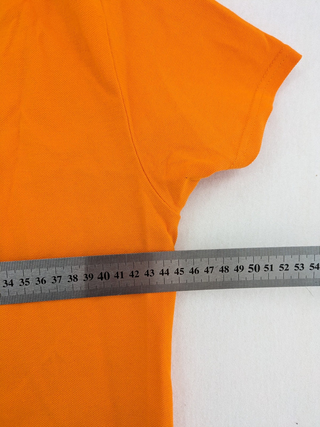 Teejays orange polo shirt with embroidered logo, classic collar, and button placket.