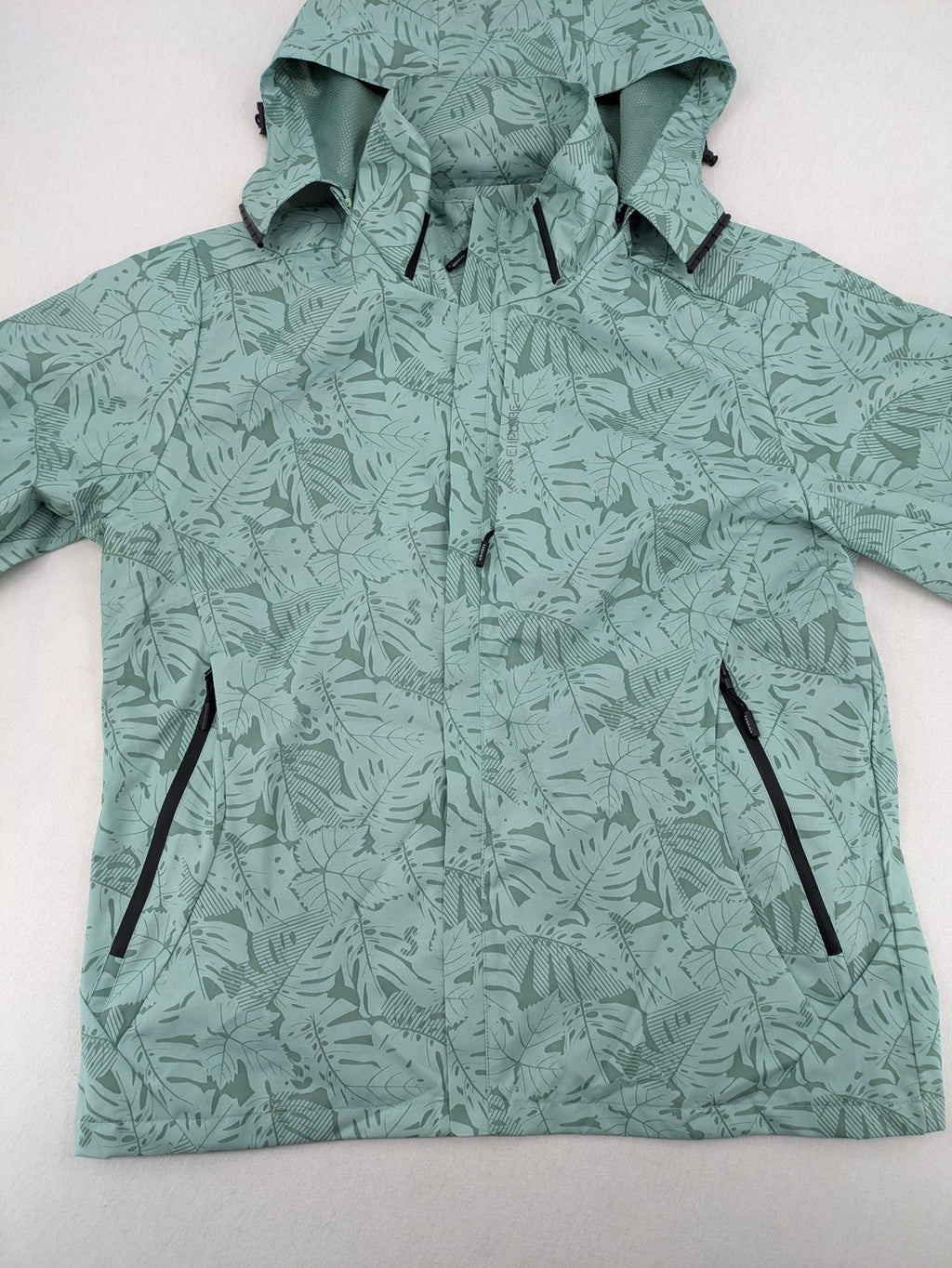 Outdoor green jacket with allover leaf print, adjustable hood, and front zipper.
