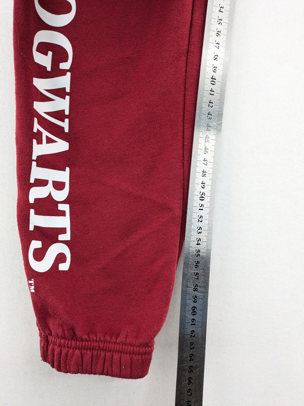 Harry Potter burgundy sweatpants featuring "HOGWARTS" print and Chibi graphic of Harry, Ron, Hermione.
