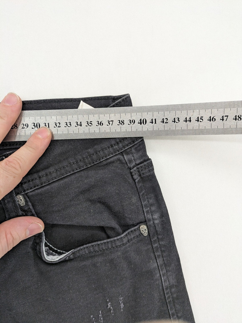 Philipp Plein black straight jeans with distressed finish and skull patch detail.