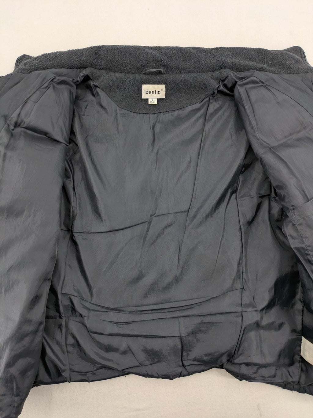 Identic black puffer jacket with quilted design and fleece-lined high collar.