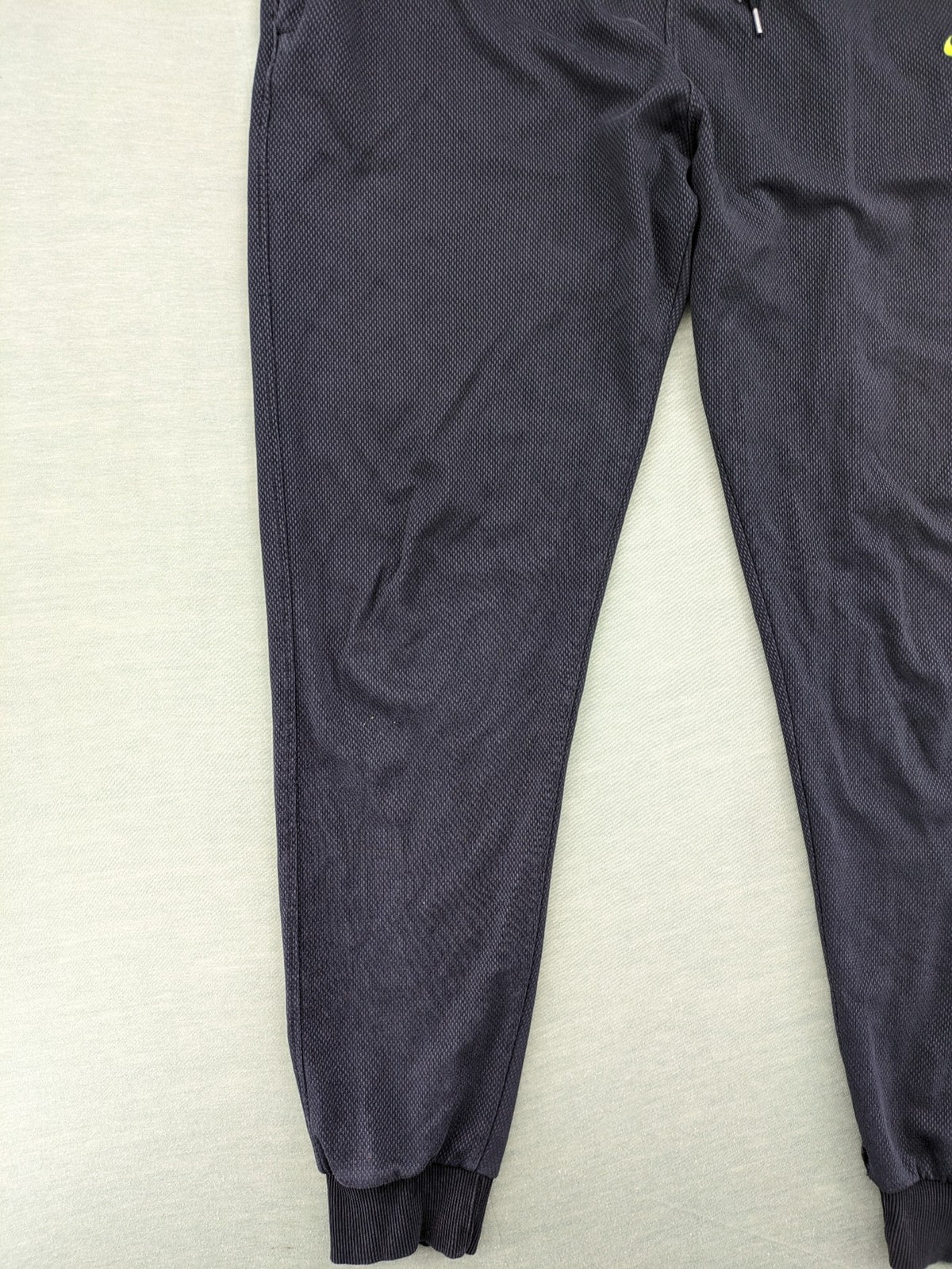 Nike F.C. grey jogger pants with elastic waistband, side pockets, and embroidered Swoosh logo.