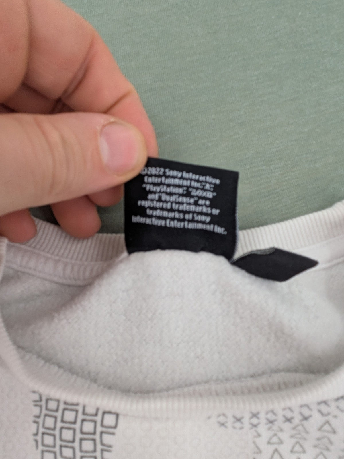 PlayStation grey sweatshirt with white logo and camo pattern featuring controller symbols.