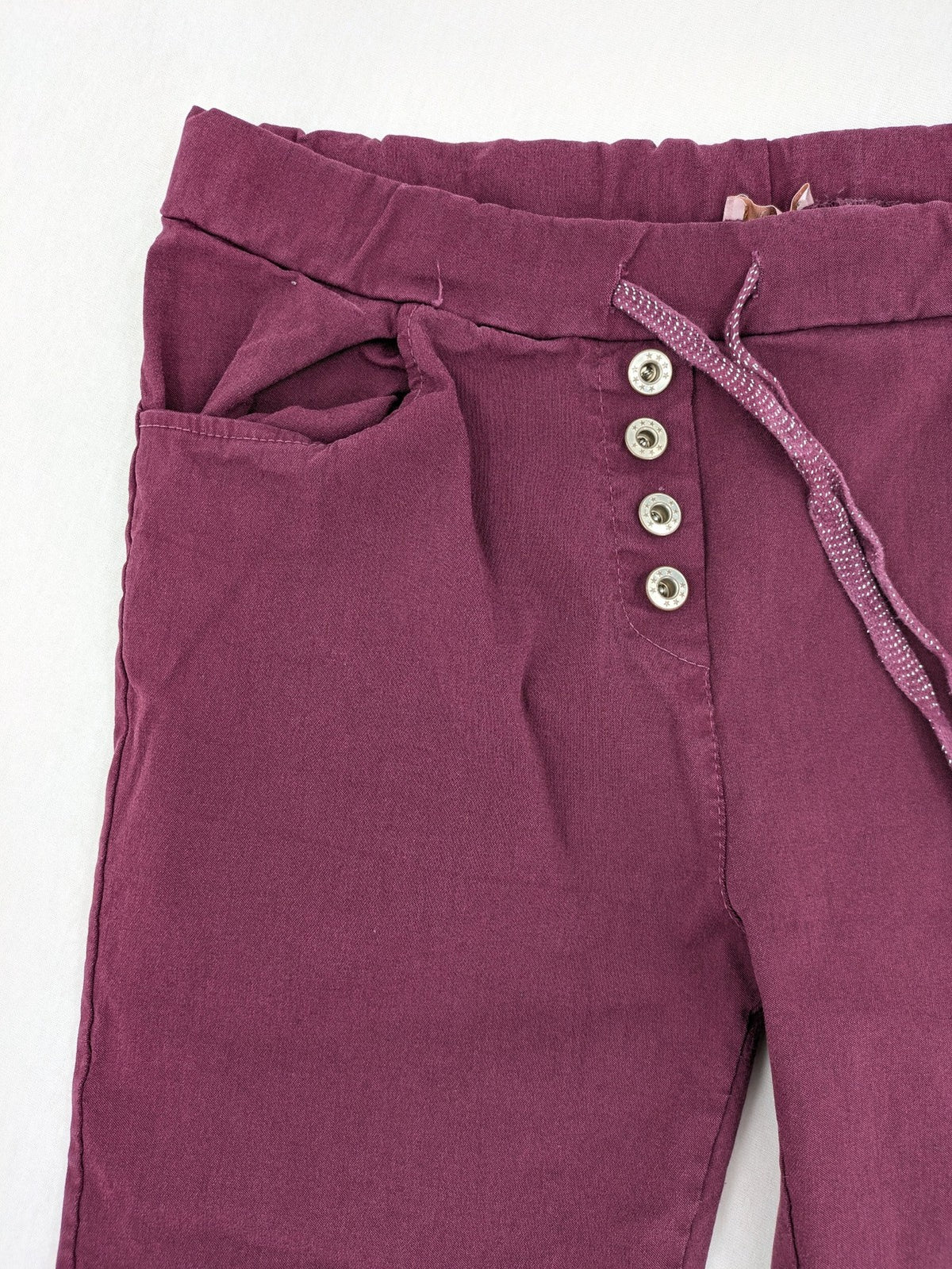 Pink Cherry pants pink stretchy fabric with decorative buttons and elastic waistband.