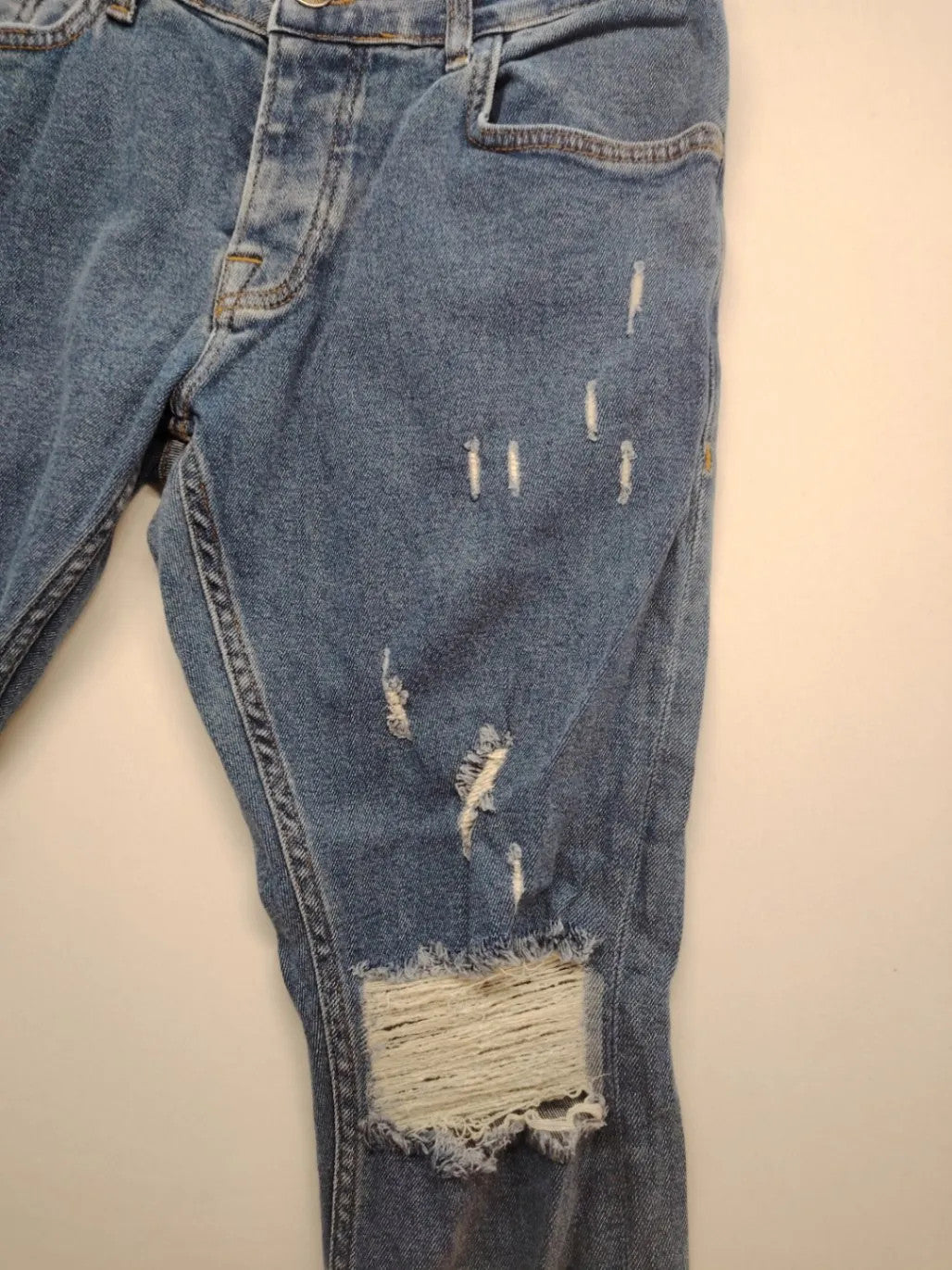 Damen blue skinny jeans with ripped details, five-pocket style, and classic button closure.