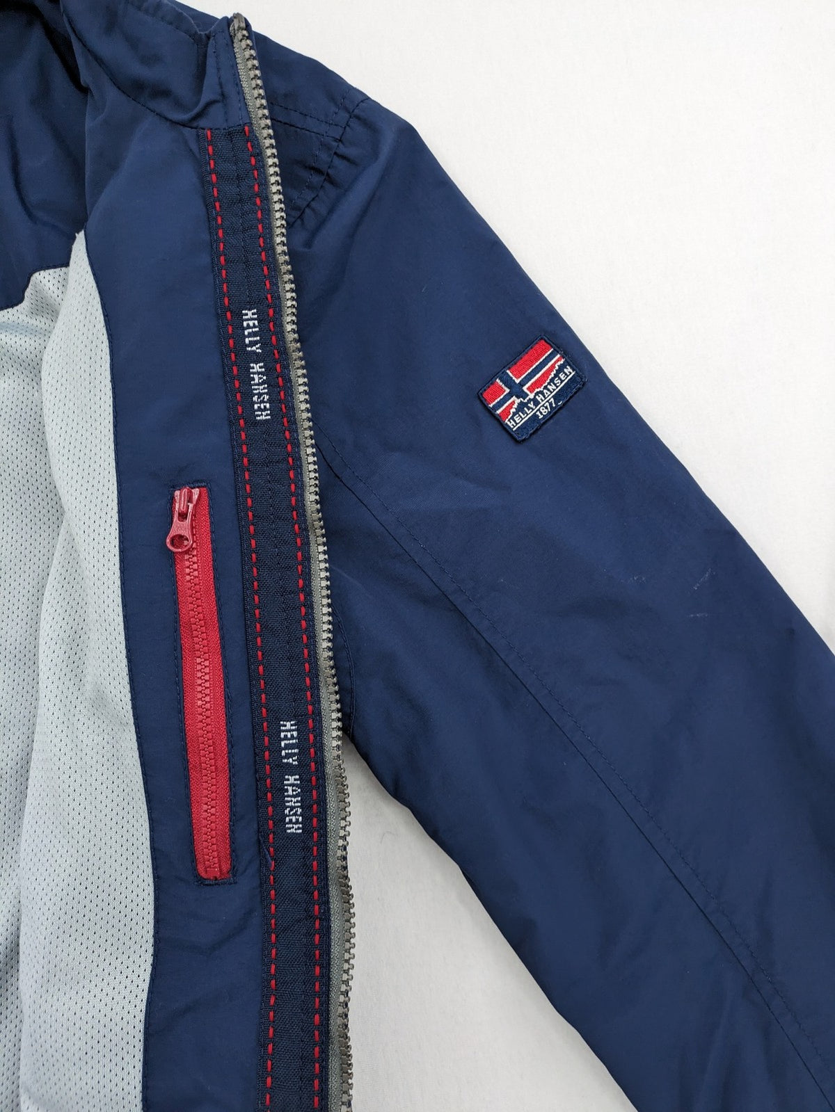 Helly Hansen navy jacket with red accents and logo, full zip, breathable mesh lining.