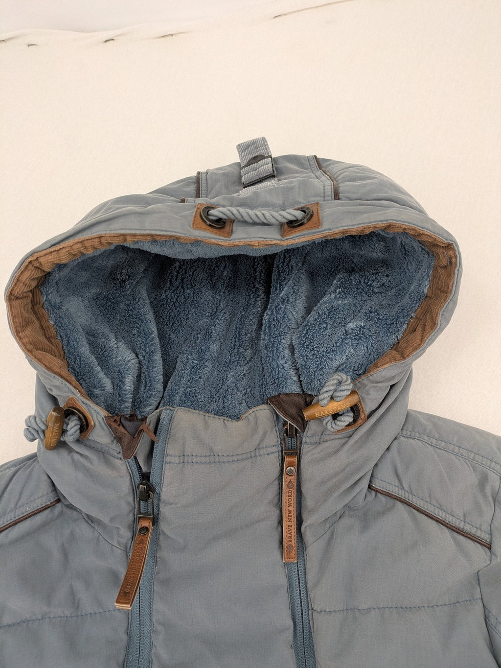 Naketano blue jacket with teddy fleece lining, hood, and leather appliqués.
