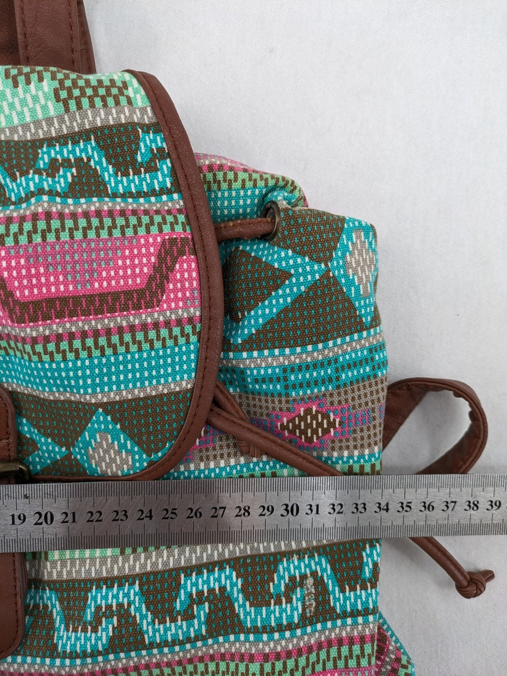 Boho multi backpack with vibrant Aztec tribal print and brown faux leather accents.