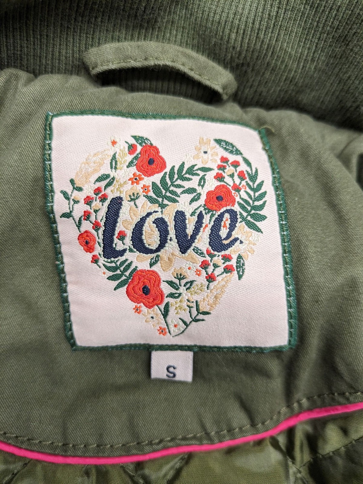 Vp Fashion khaki parka coat with "Bloomin' Lovely" floral embroidery and quilted lining.