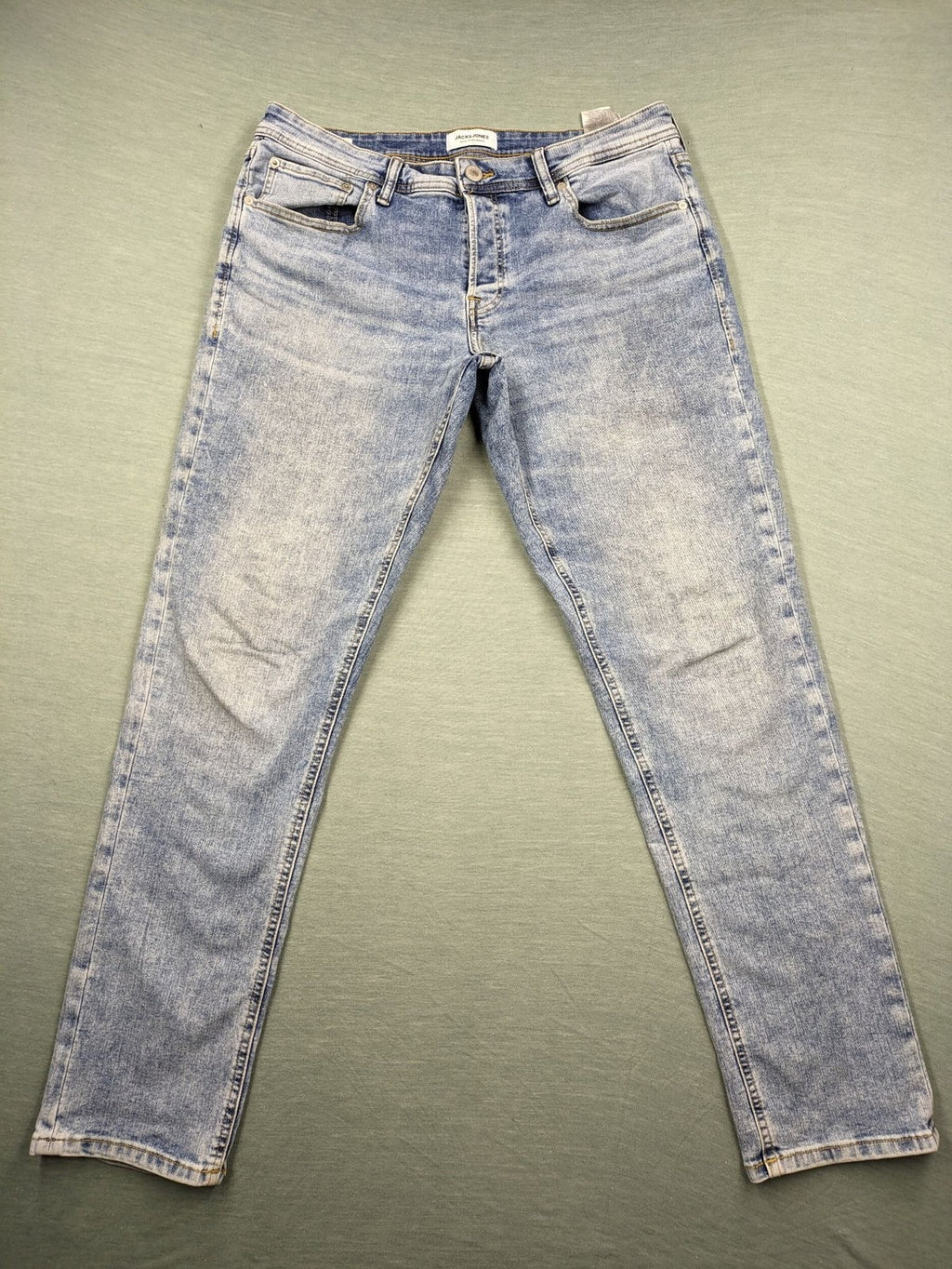 Jack & Jones blue slim fit jeans with button fly and light wash denim texture.