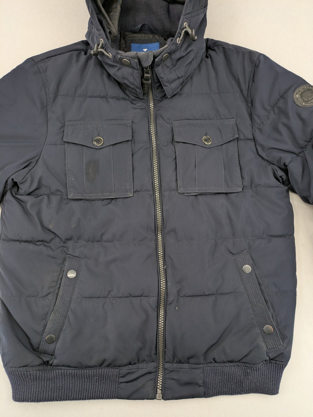Tom Tailor navy puffer jacket with quilted design and adjustable hood, featuring multiple pockets.