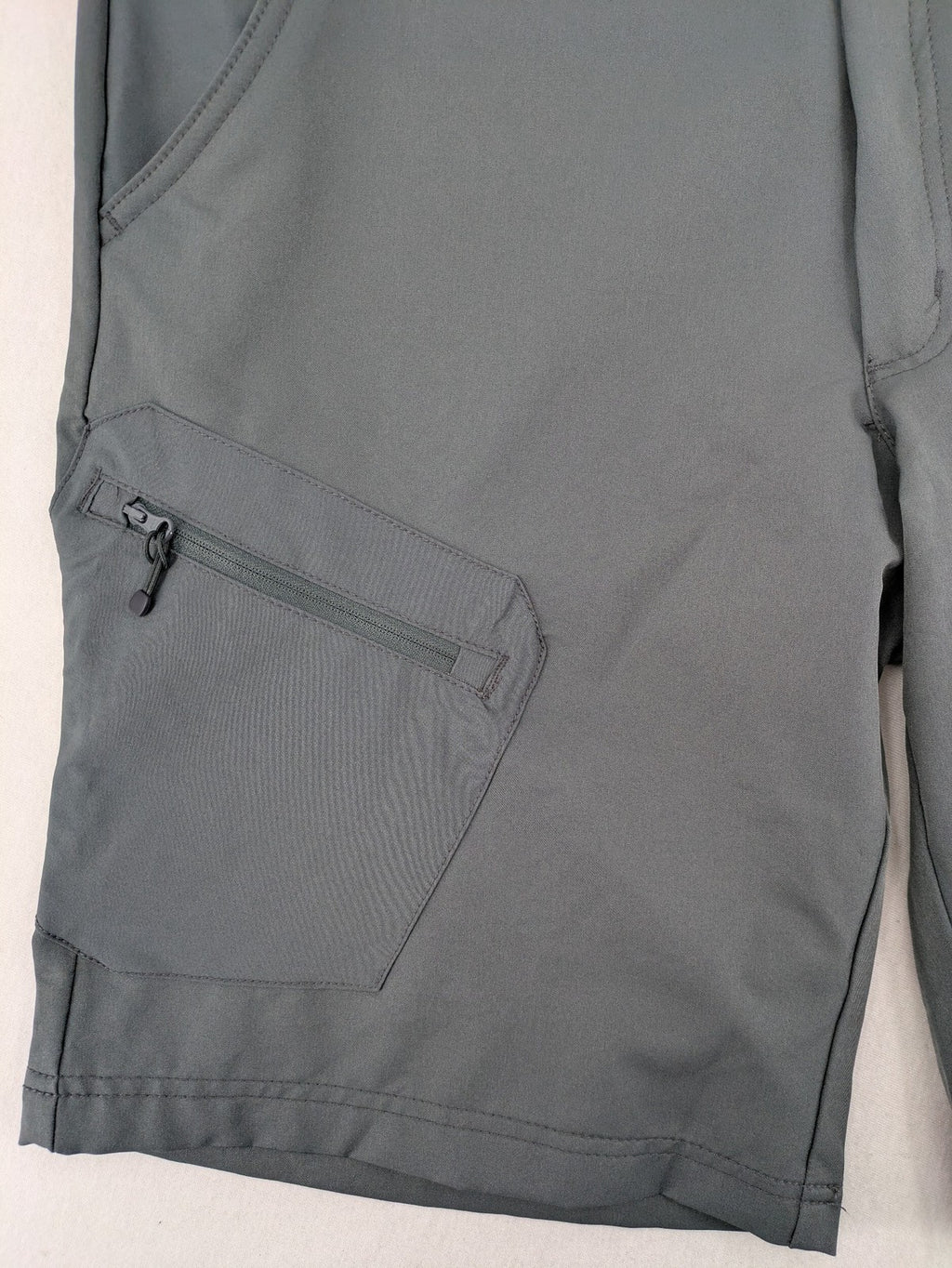 Outdoor grey functional shorts with adjustable velcro waistband and zippered leg pocket.