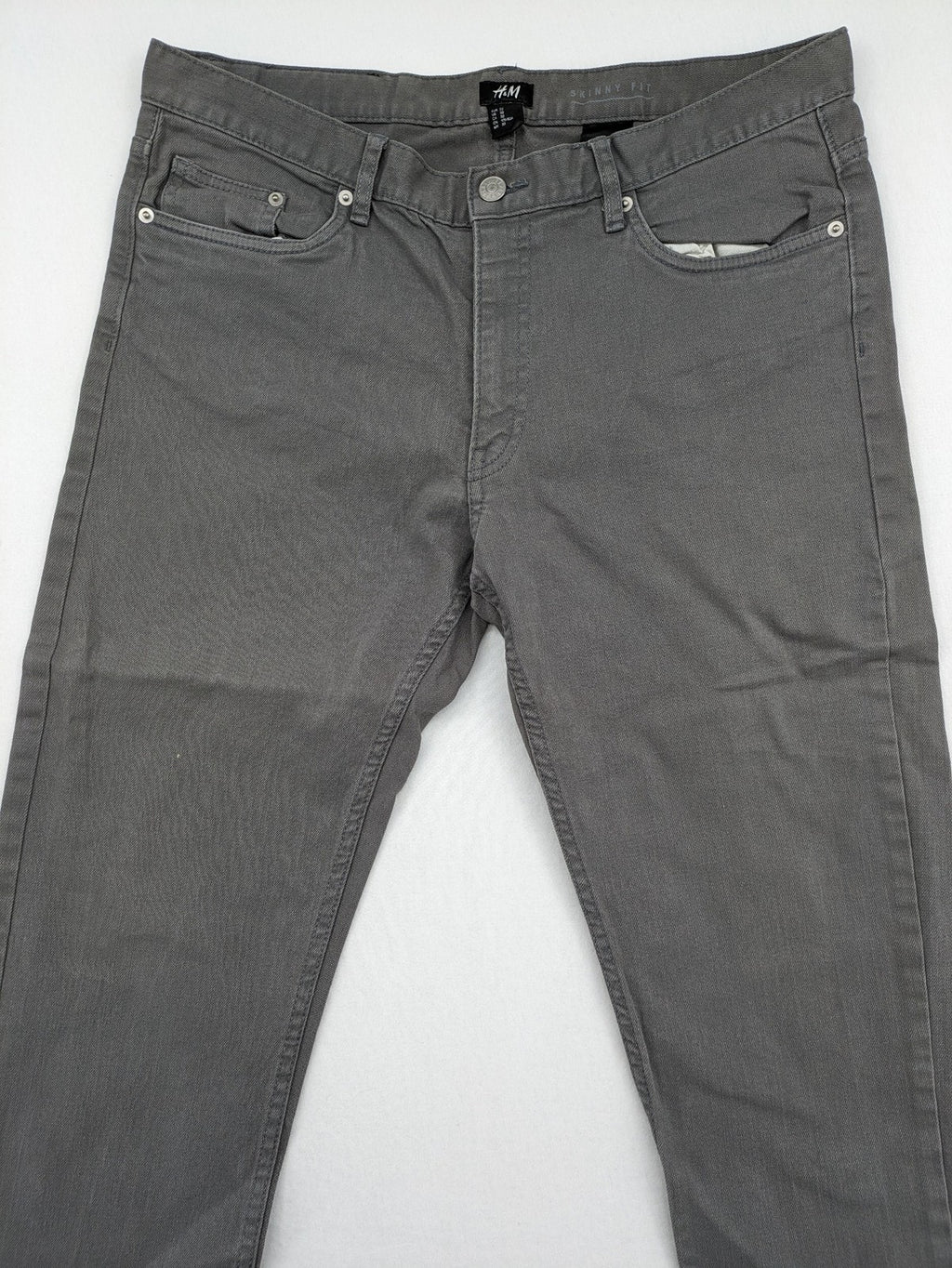 H&M grey skinny fit jeans with button closure and five-pocket design, cotton-elastane blend.
