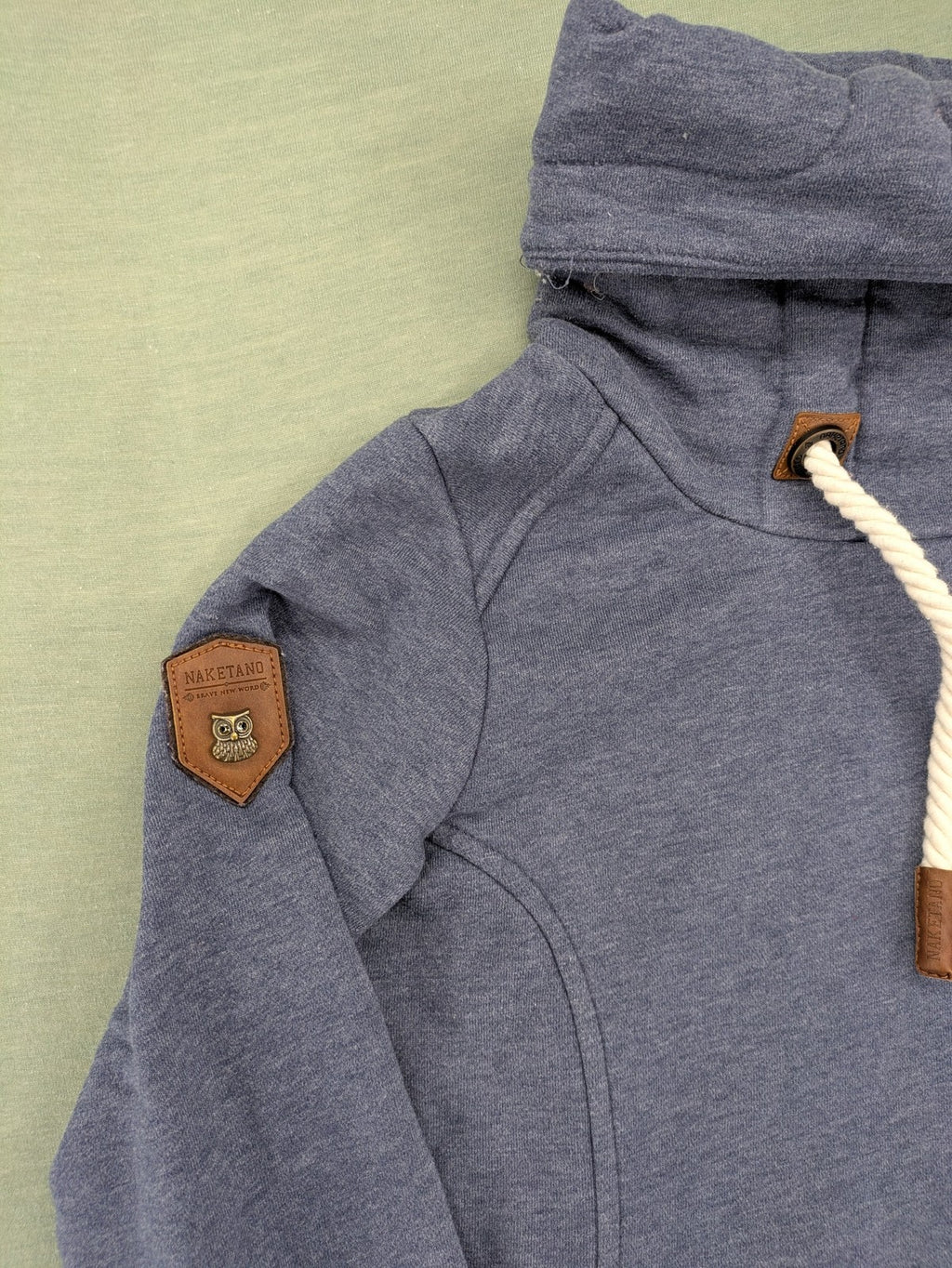 Naketano grey turtle neck jumper with thick drawstring and leather logo appliqué.