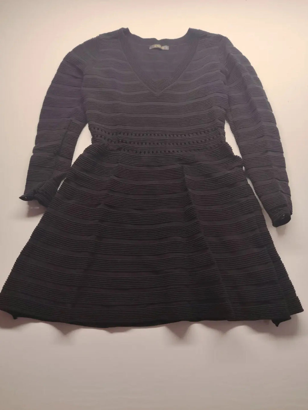 Supertuga black ribbed dress with V-neck, long sleeves, and pointelle detail at waist.