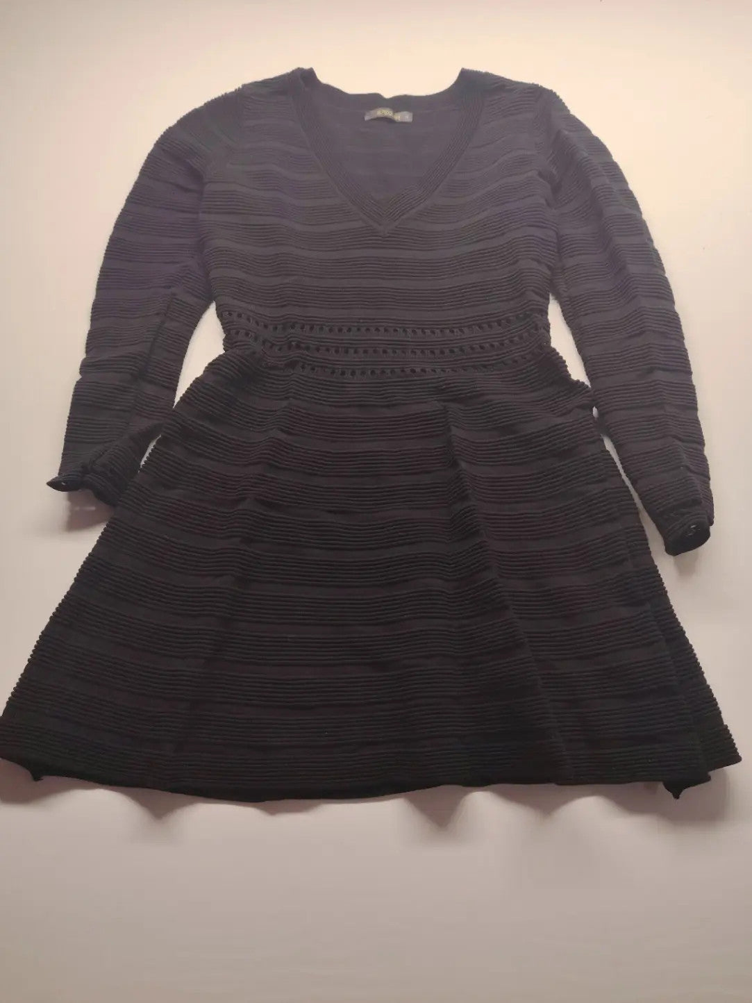 Supertuga black ribbed dress with V-neck, long sleeves, and pointelle detail at waist.