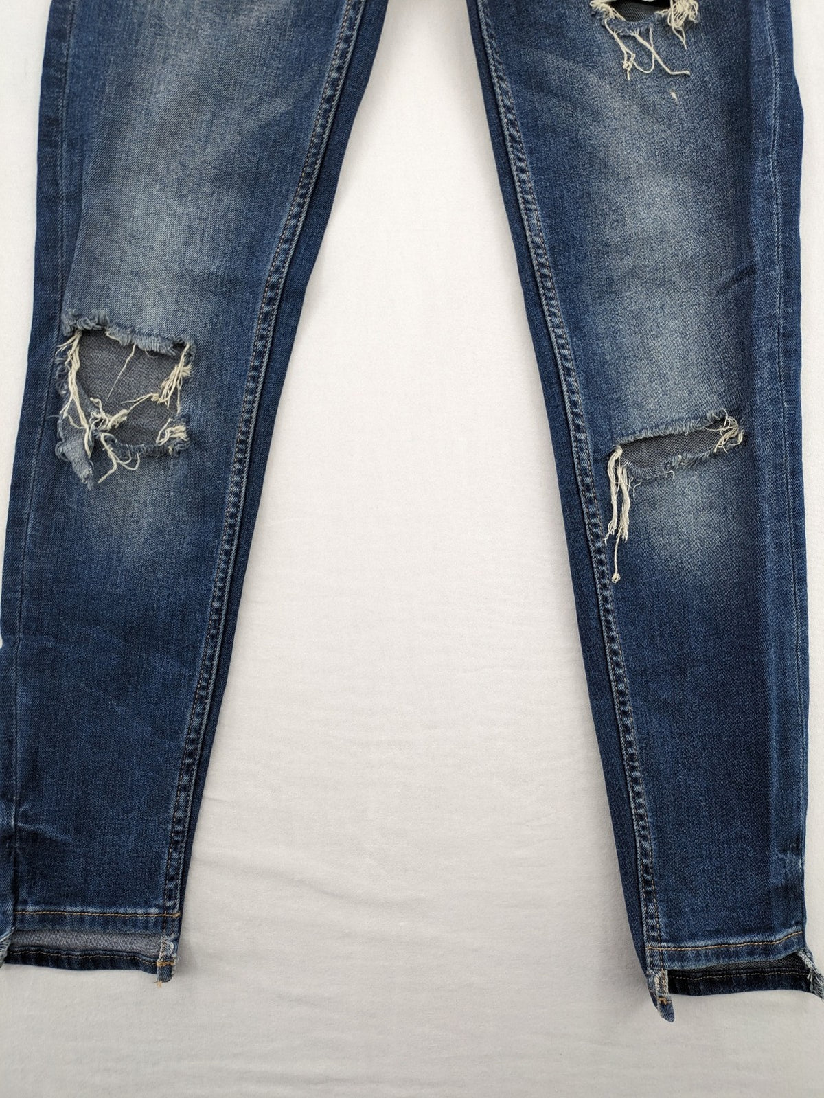 Zara Basic blue skinny jeans with destroyed knee details and frayed hem.