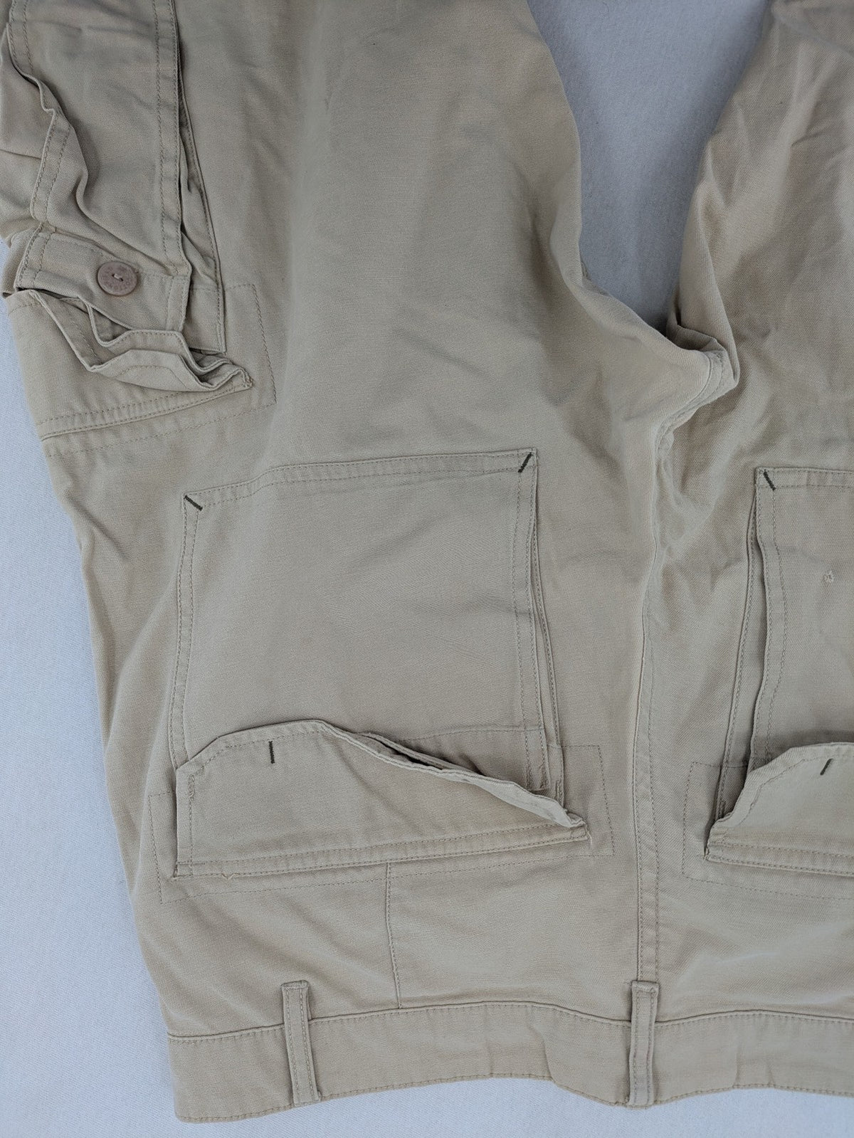 Cottonfield beige cargo pants with multiple pockets and button flaps.