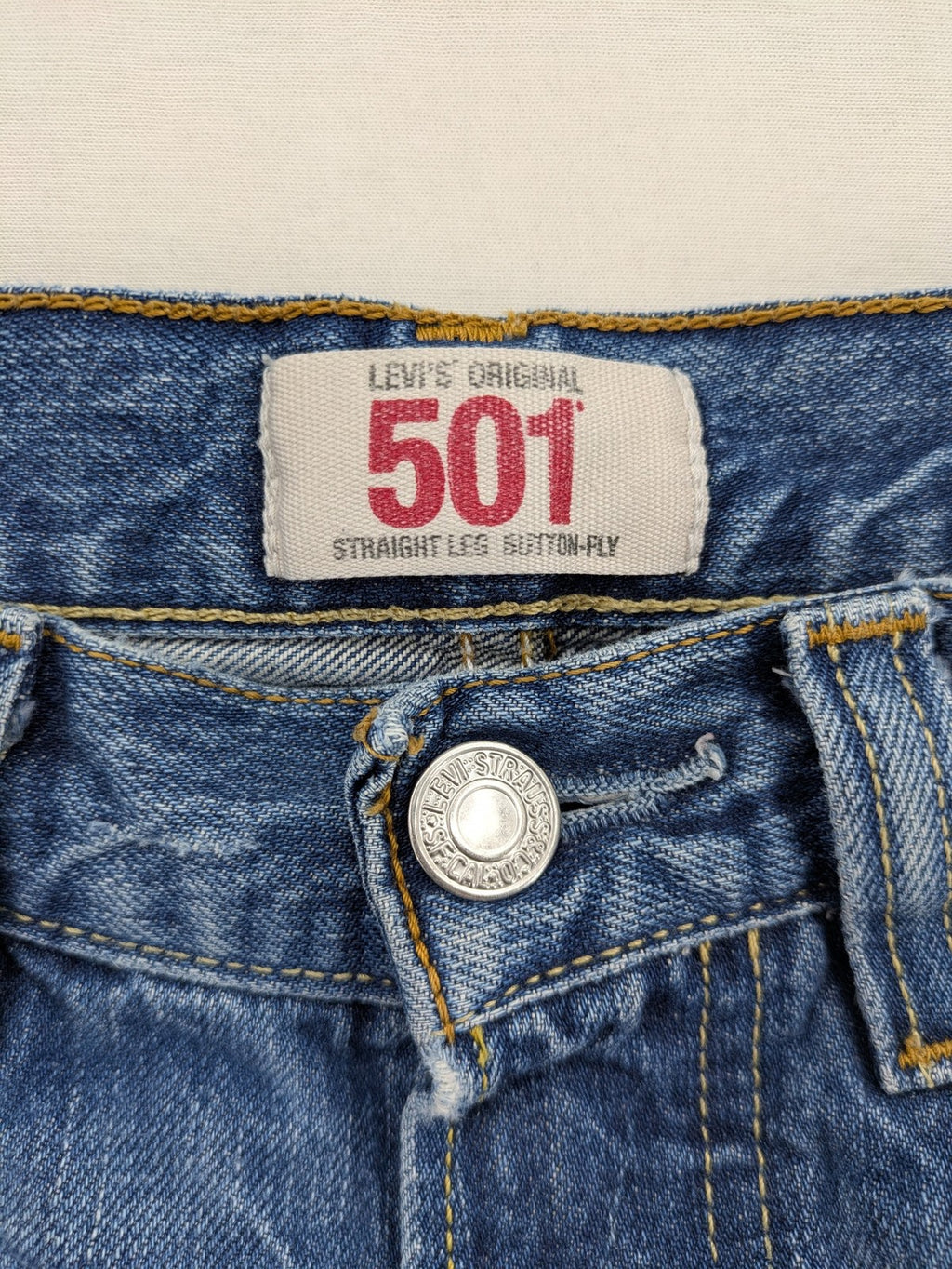 Levi's blue straight jeans with button-fly and distressed knee rips.