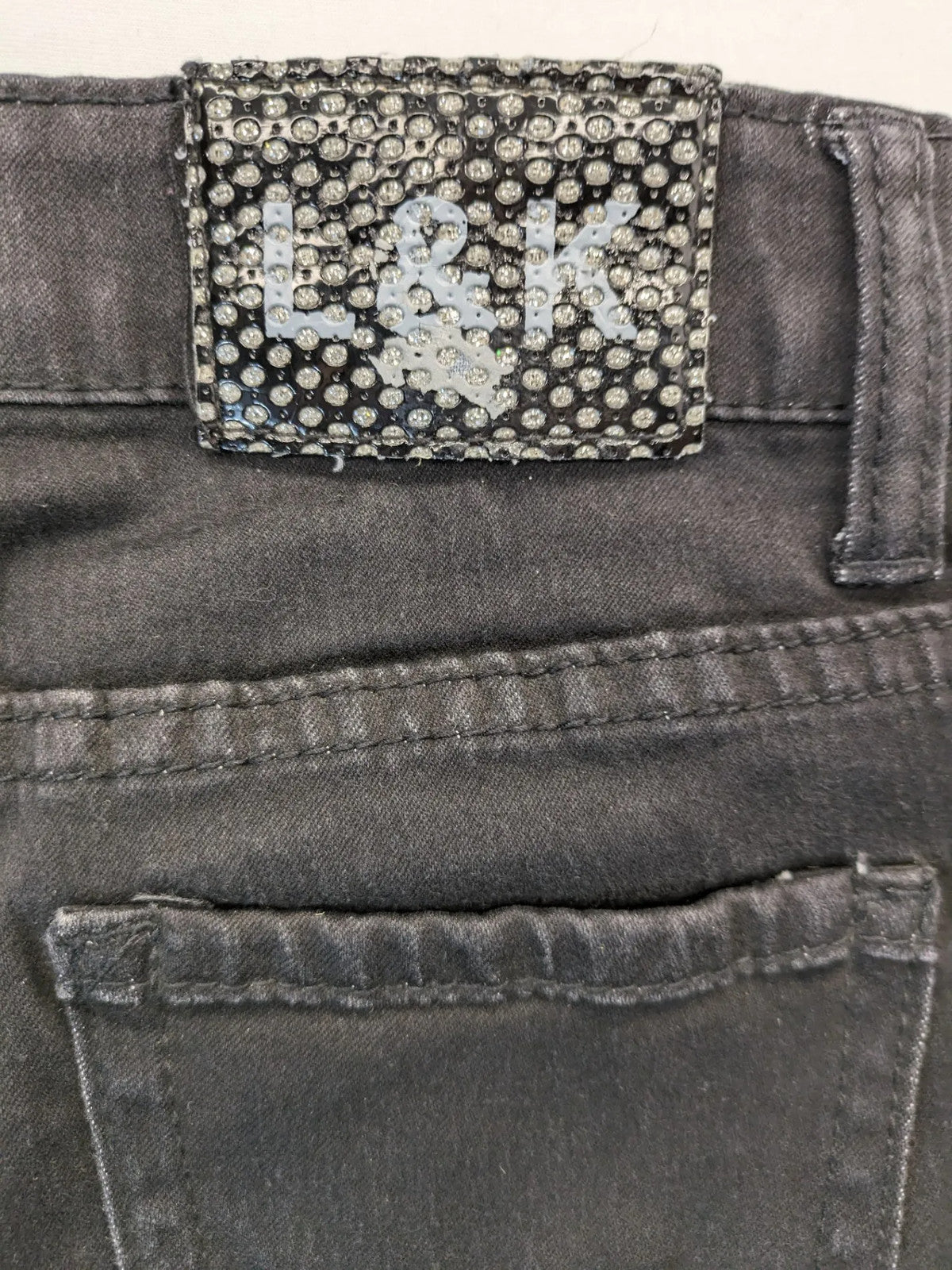 L & K Kaha black straight jeans with rhinestone logo patch and classic 5-pocket design.