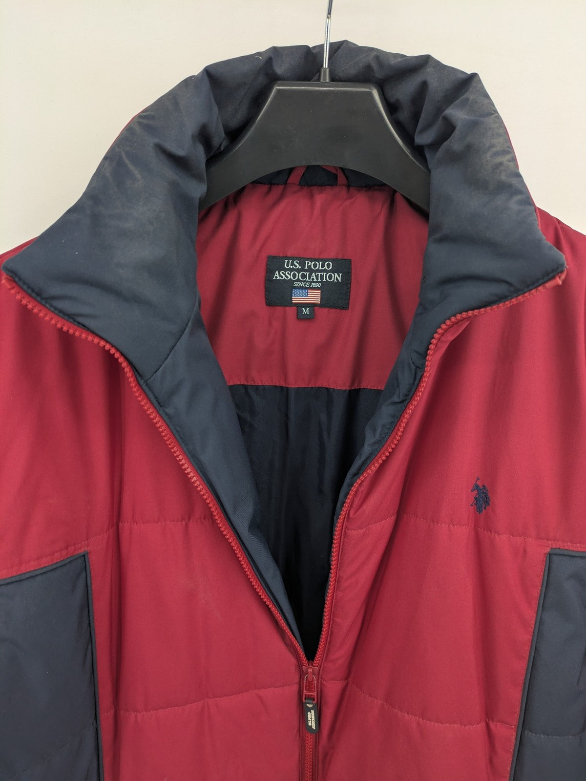 US Polo Assn. puffer jacket navy red two-tone design with embroidered logo and zip pockets.