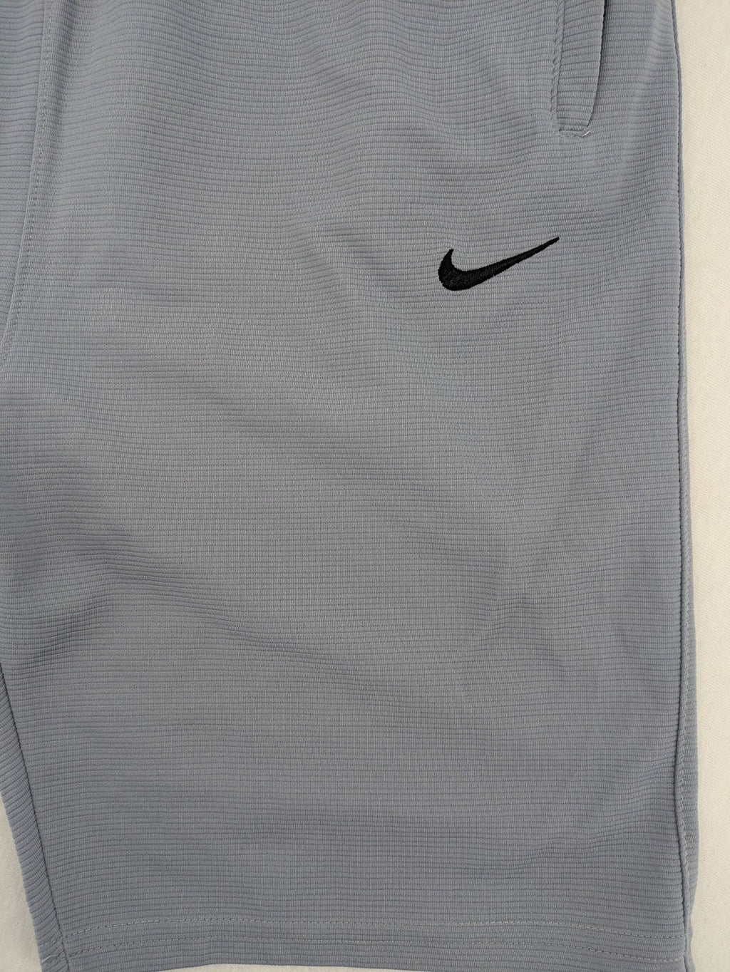 Nike grey shorts with Dri-FIT technology, elastic waistband, and zippered pockets.