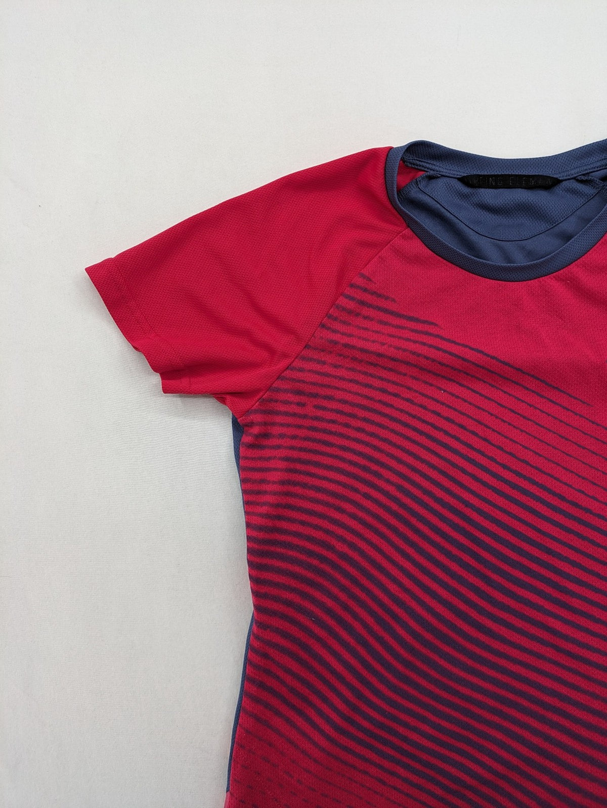 Muster blue and red short-sleeve functional shirt with dynamic wave pattern and raglan sleeves.