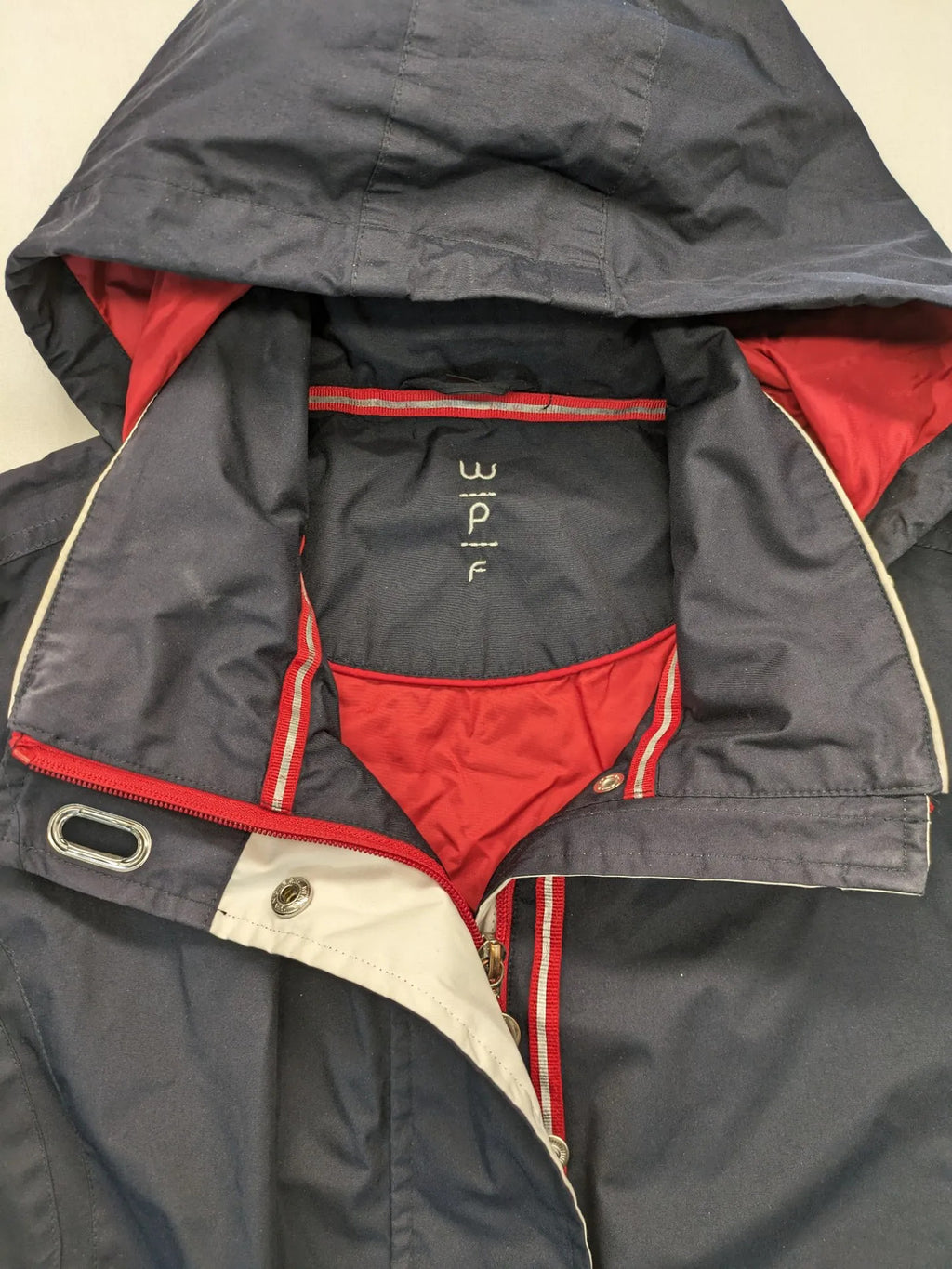 WPF grey outdoor jacket with red lining, zip closure, and hood.