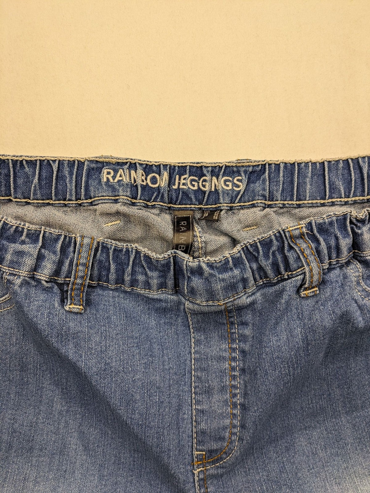 Rainbow blue straight jeans with elastic waistband and decorative knee stitching.