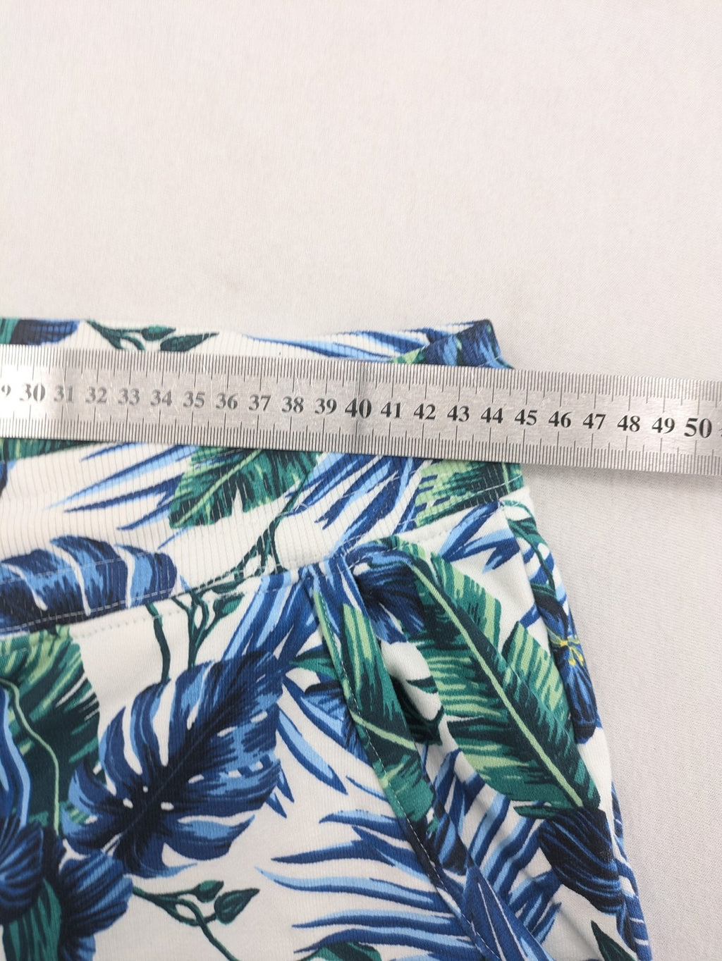 Nils Sundström blue and green tropical floral shorts with white background and elastic waistband.