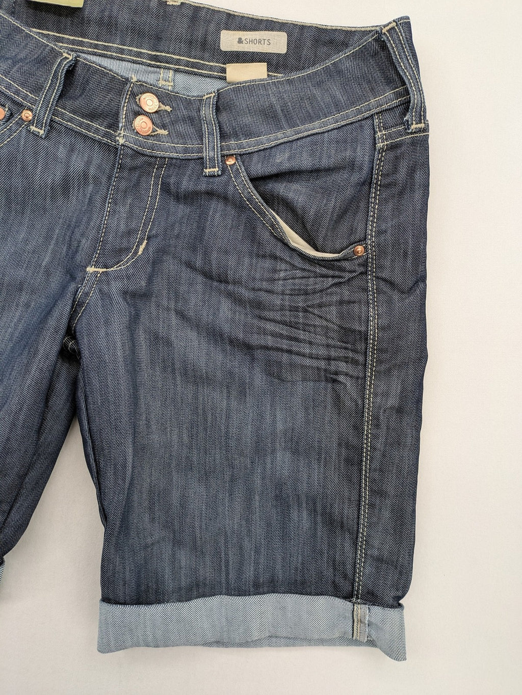 H&M blue denim shorts with rolled cuffs and back patch pockets, mid-rise fit.