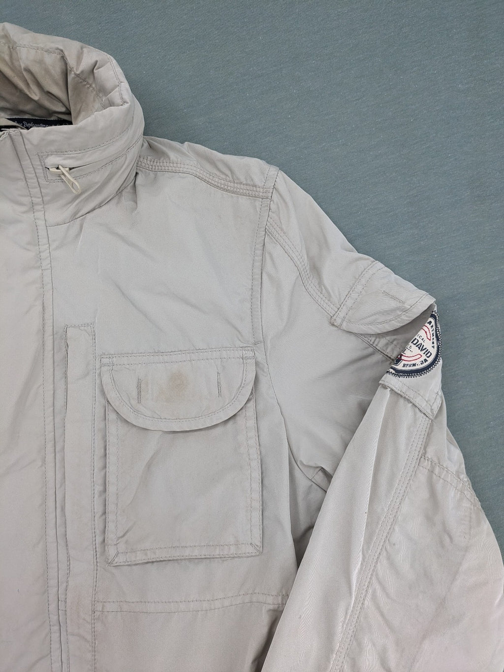 Camp David beige field jacket with logo patches, standing collar, and multiple pockets.