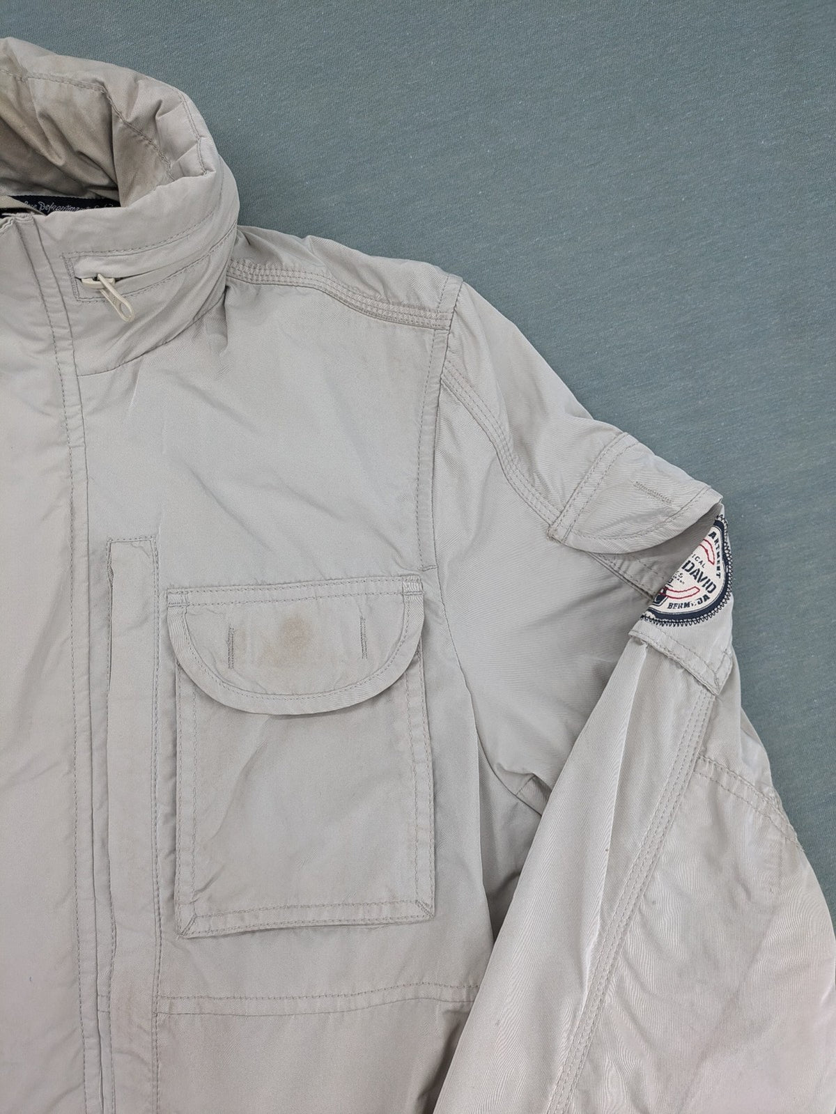 Camp David beige field jacket with logo patches, standing collar, and multiple pockets.
