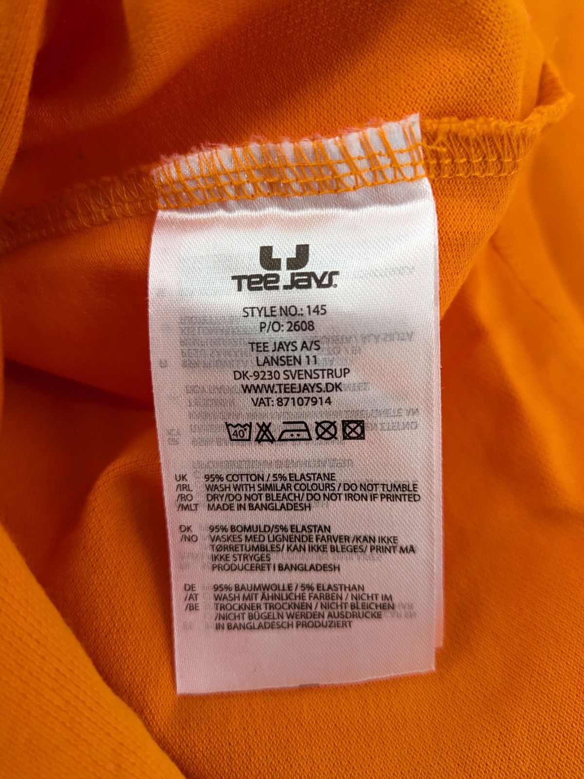 Teejays orange polo shirt with embroidered logo, classic collar, and button placket.