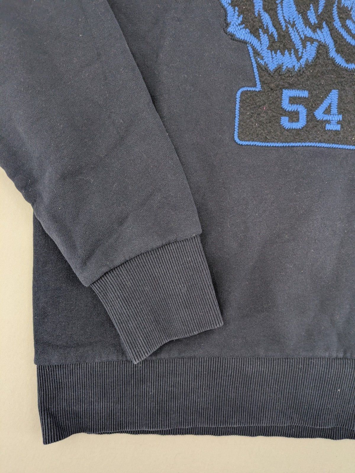 Superdry navy sweatshirt with embroidered tiger graphic and "JPN 54" chenille detail.