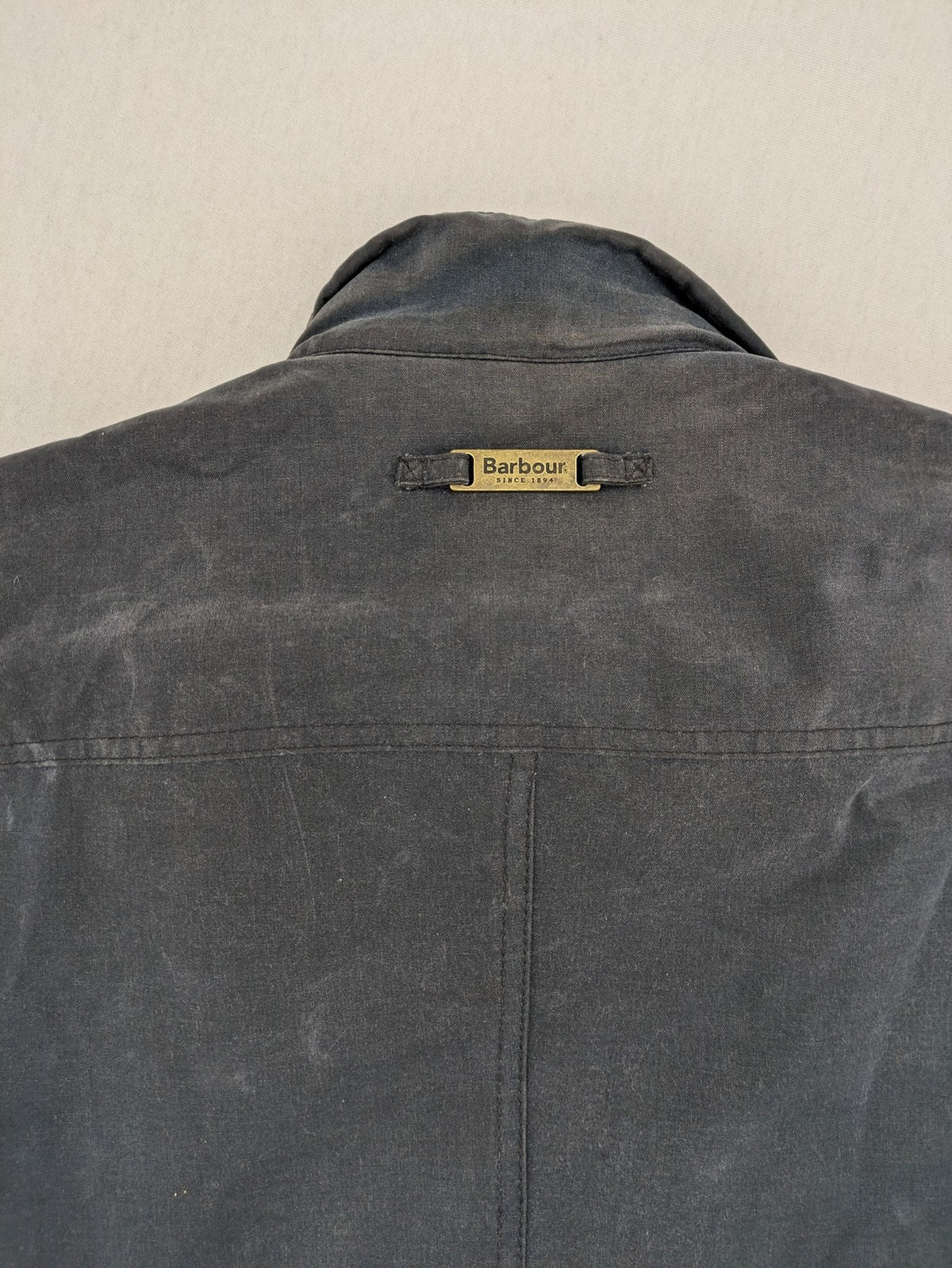 Barbour navy wax jacket with quilted lining and leather elbow patches, tartan interior.