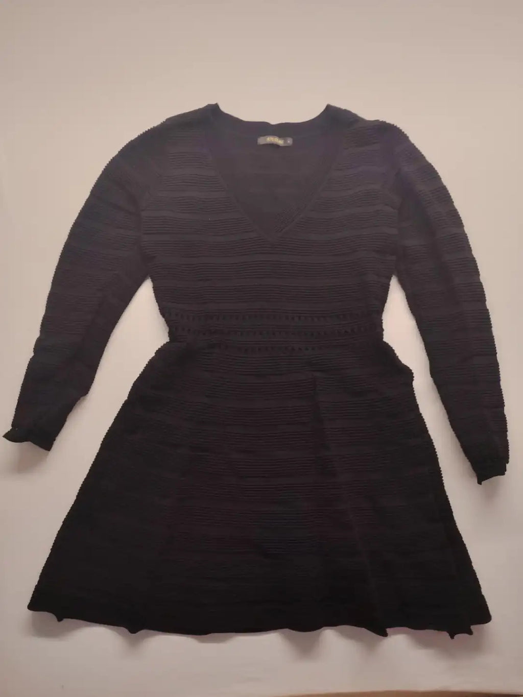 Supertuga black ribbed dress with V-neck, long sleeves, and pointelle detail at waist.