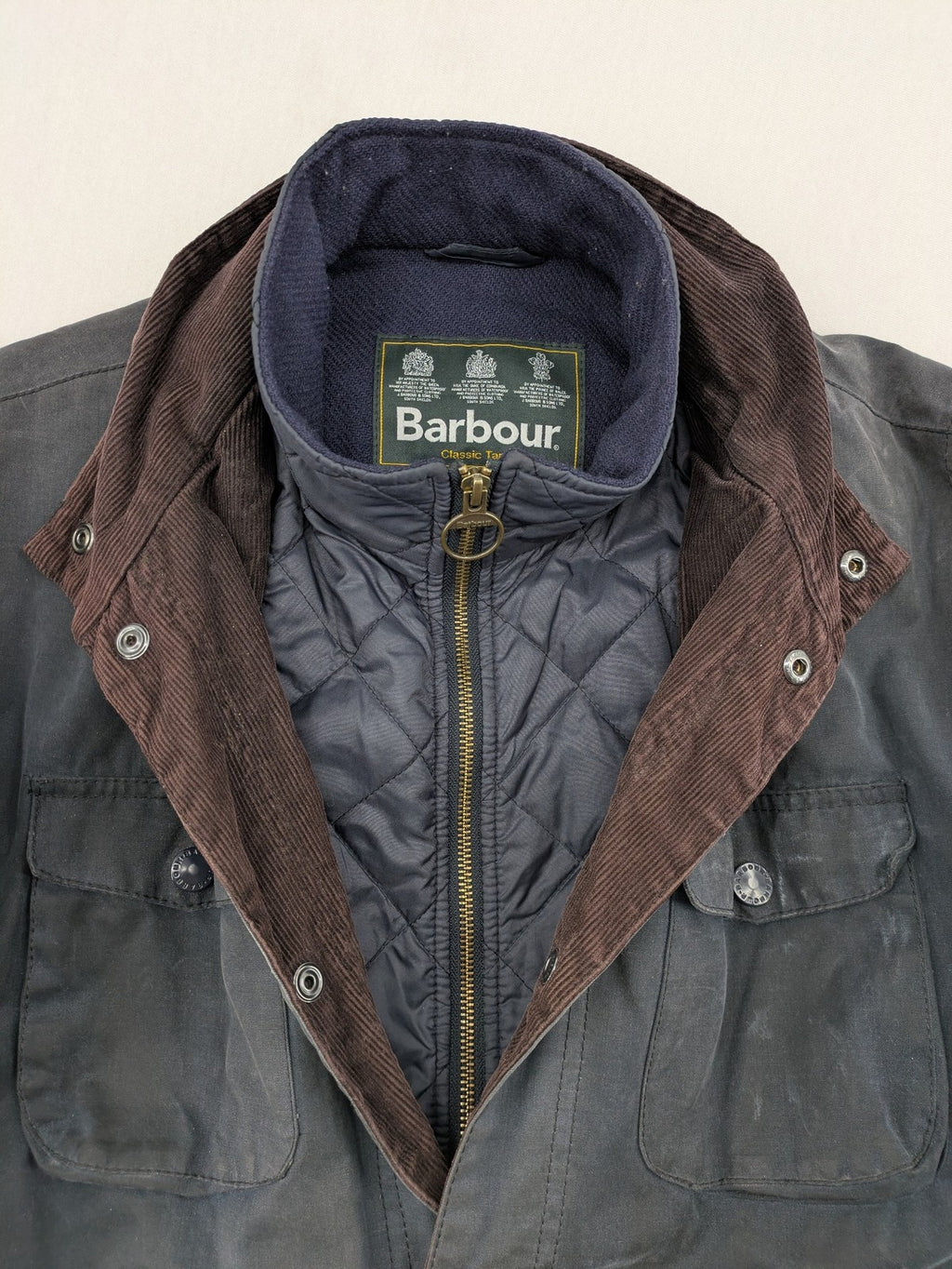 Barbour navy wax jacket with quilted lining and leather elbow patches, tartan interior.