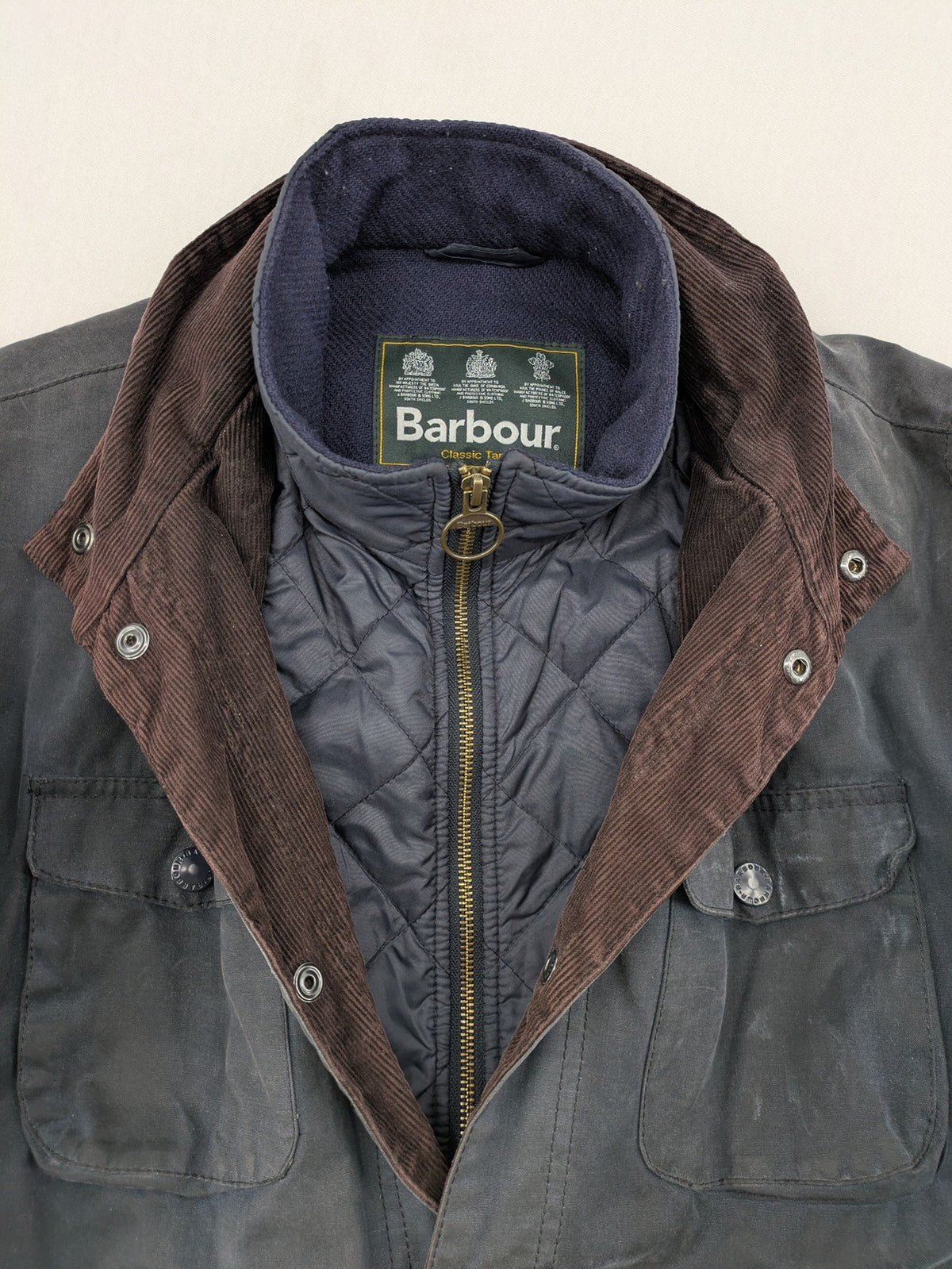 Barbour navy wax jacket with quilted lining and leather elbow patches, tartan interior.