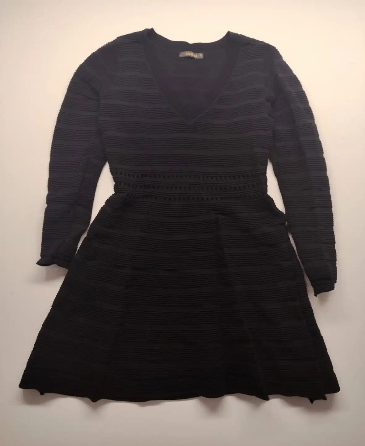 Supertuga black ribbed dress with V-neck, long sleeves, and pointelle detail at waist.