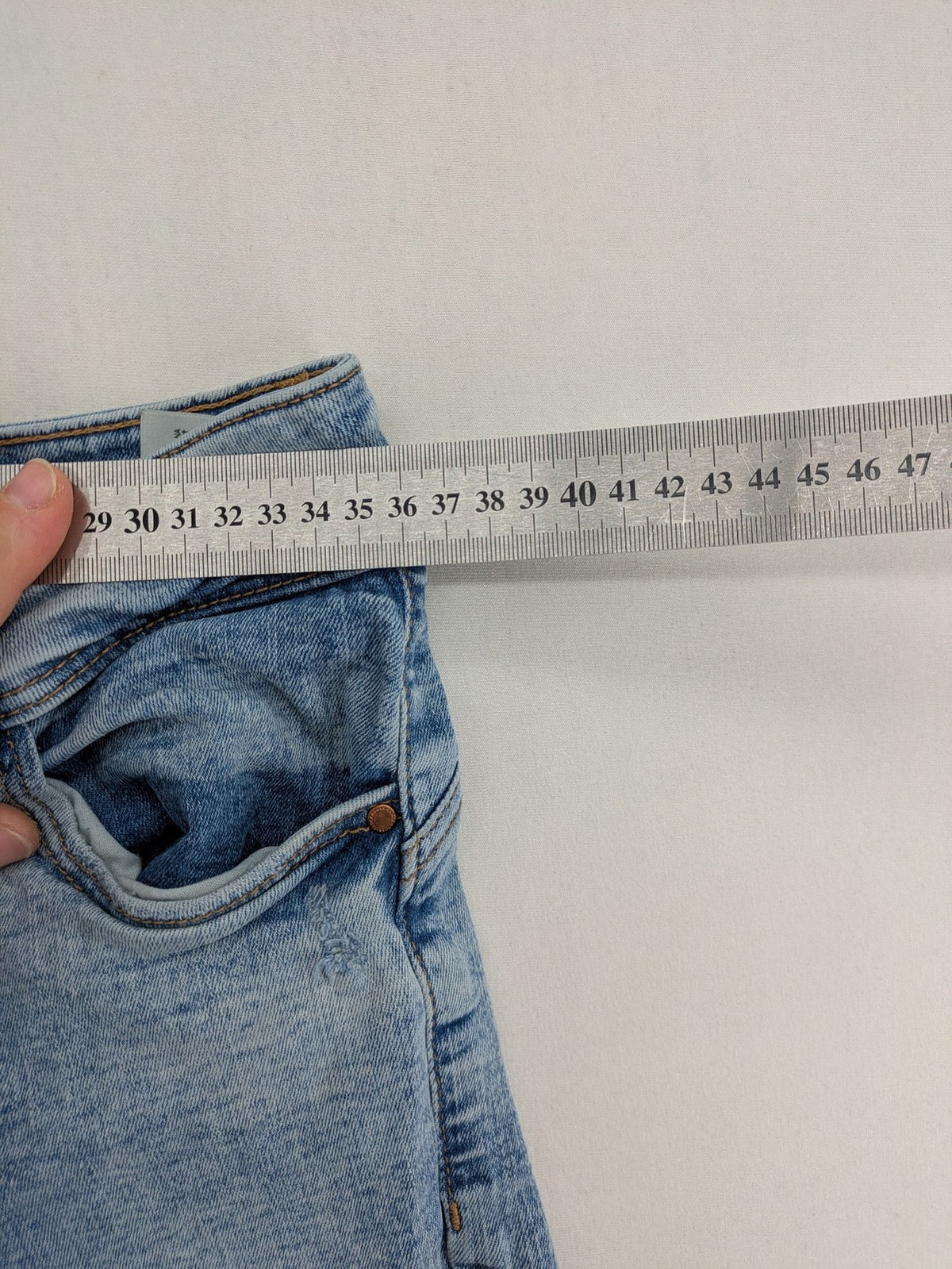 Clockhouse blue skinny jeans with distressed details and frayed hem, mid-rise fit.