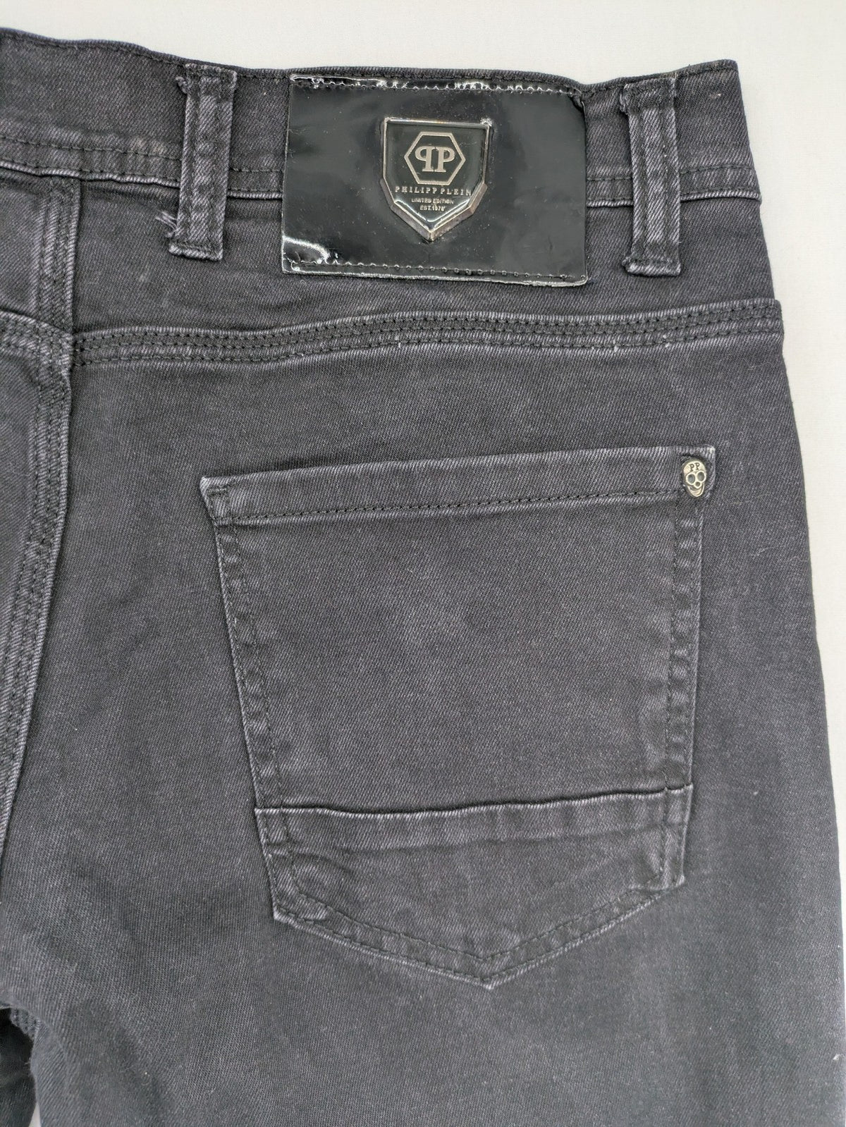 Philipp Plein black straight jeans with distressed finish and skull patch detail.