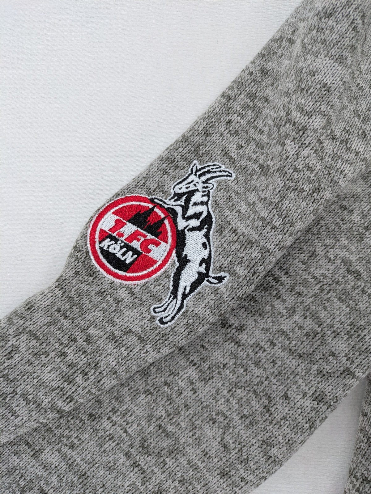 1. FC Köln grey fleece jacket with embroidered logo and hood, perfect for fans.